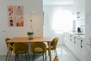 a kitchen with a wooden table and yellow chairs at Lujoso apartamento con piscina compartida 3 in Seville