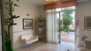 Hotel Rosati في ريميني: غرفة معيشة بها كرسي أبيض وباب زجاجي منزلق