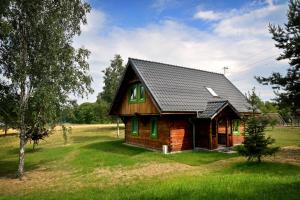 a small wooden house with a black roof at Domy Nad Drawskim in Siemczyno