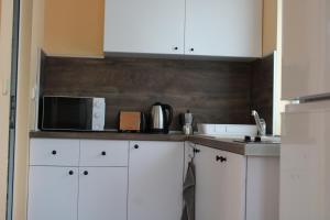 a kitchen with white cabinets and a microwave at Къща за гости Света Марина in Krapets