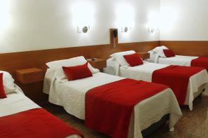 a room with three beds with red and white sheets at HL Hotel in Cipolletti +13 photos
