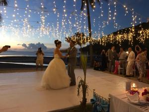 a bride and groom dancing at a beach wedding with lights at Phangka Paradise Resort in Taling Ngam Beach