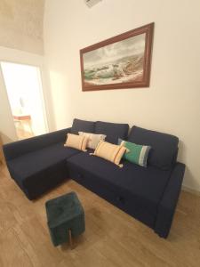 eine blaue Couch in einem Wohnzimmer mit einem Gemälde in der Unterkunft LUNA in Monopoli
