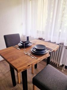 a wooden table with plates and wine glasses on it at Wasserfälle Apartments in Sasbachwalden