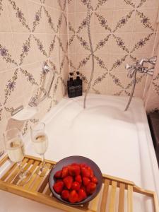 a tray with a bowl of strawberries and two glasses of wine at Wasserfälle Apartments in Sasbachwalden