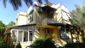una casa amarilla con ventanas y palmeras en Konakli Beach Villa, en Konaklı