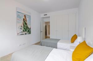 プエルト・デ・サンティアゴにあるOasis del Marの白い壁の客室で、ベッド2台、黄色の枕が備わります。