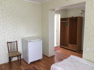 a room with a bed and a chair and a refrigerator at Эдем in Cholpon-Ata