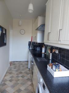 a kitchen with black counter tops and white cabinets at ISLAY House,Comfortable Home with private garden, Pencaitland, East Lothian, Scotland in Pencaitland