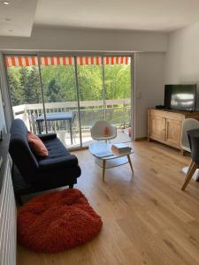 a living room with a couch and a table at Superbe T3 lumineux sur parc arboré avec piscine in Anglet