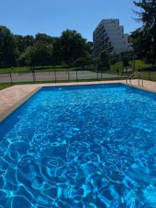 een zwembad met blauw water in een park bij Superbe T3 lumineux sur parc arboré avec piscine in Anglet