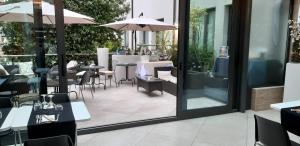 eine Terrasse mit Tischen, Stühlen und einem Sonnenschirm in der Unterkunft Continental Urban Art Hotel in Zola Predosa