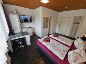 a bedroom with two beds and a desk and a tv at Pension Hamburg in Bad Grund