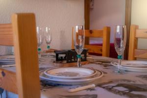 una mesa con copas de vino y platos en ella en Le Rossane 26m Balcon vue, en Aillon-le-Jeune