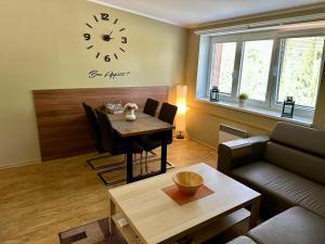 a living room with a table and a clock on the wall at Apartman DvacetSedm in Lipno nad Vltavou