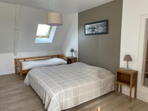 een slaapkamer met 2 bedden, 2 tafels en een raam bij La Ferme Cap Fréhel in Hénanbihen