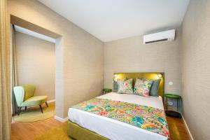 ポルトにあるCasas do Porto - Ribeira Apartmentsの小さなベッドルーム(ベッド1台、椅子付)