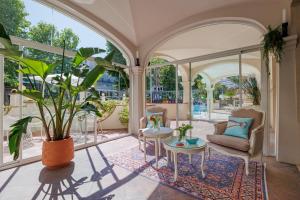 un soggiorno con ampie finestre e una pianta in vaso di Parco dei Principi Boutique Hotel a Rimini