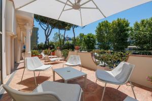 a patio with chairs and a table and an umbrella at Parco dei Principi Boutique Hotel in Rimini