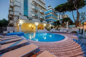 una piscina in un hotel con sedie e un edificio di Parco dei Principi Boutique Hotel a Rimini