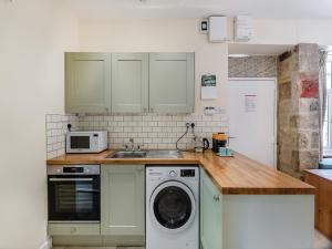 a kitchen with a washing machine and a microwave at Church Cottage in Two Dales