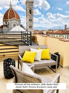 a balcony with yellow pillows and a clock tower at Hotel Perseo in Florence