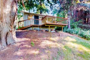 a house with a large deck in the woods at Calamity Cabin in Gig Harbor