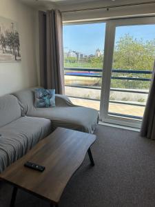 a living room with a couch and a table and a window at Gunwharf Quays Harbour Apartments in Portsmouth