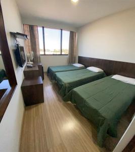 um quarto com duas camas e uma televisão em Hotel Itamaraty em Curitiba