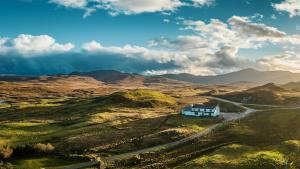 une maison sur le côté d'une route dans les montagnes dans l'établissement Loch Erisort Hotel, à Balallan