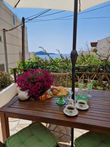 een houten tafel met eten en bloemen erop bij Bel Posto Apartment in Dubrovnik