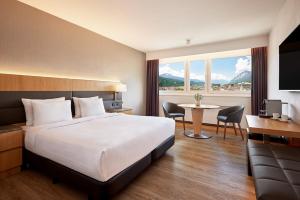 a hotel room with a large bed and a table at AC Hotel by Marriott Innsbruck in Innsbruck