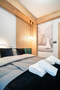 a bedroom with a bed with two white towels on it at Apartament Niebiańska Polana by Apart Concept Podhale in Kościelisko
