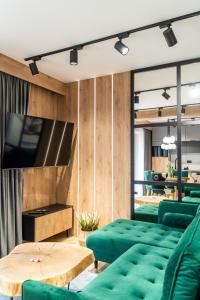 a living room with green furniture and a flat screen tv at Apartament Niebiańska Polana by Apart Concept Podhale in Kościelisko
