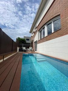 - une piscine en face d'un bâtiment avec une maison dans l'établissement Casa con piscina cerca de la playa, à Vidreres