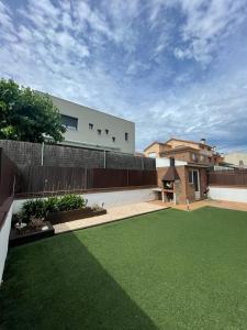 une cour avec une clôture et une cour d'herbe verte dans l'établissement Casa con piscina cerca de la playa, à Vidreres