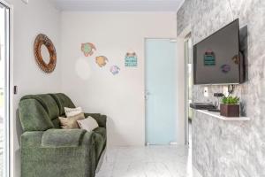 een woonkamer met een groene stoel en een televisie bij Casa de férias familiar com linda vista à 300m da Meia Praia de Navegantes in Navegantes
