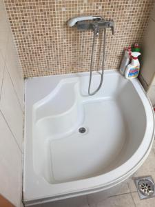 a white bath tub with a shower in a bathroom at Central apartment in Pristina +14 photos