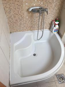 a white bath tub with a shower in a bathroom at Central apartment in Prishtinë