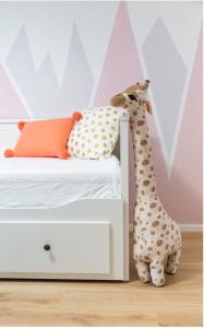Una giraffa giocattolo è in piedi accanto a un letto di The Garden Loft a Francoforte sul Meno