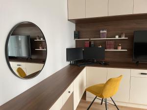 a mirror hangs above a desk with a yellow chair at The Garden Loft in Frankfurt/Main