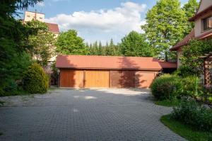 a garage with a brown door on a driveway at Apartament w Alejce in Rabka