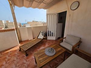 a living room with a couch and a chair on a balcony at Ático Pola in Santa Pola