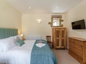 1 dormitorio con 1 cama, vestidor y TV en Church Cottage en Two Dales