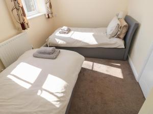 two beds in a small room with sunlight shining on them at 66 Dale Grove in Leyburn