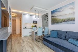 a living room with a blue couch and a kitchen at Ambria Apartments Ułańska in Świnoujście