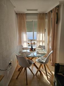 a dining room with a glass table and chairs at Ático Pola in Santa Pola