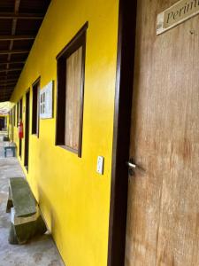 a yellow wall with a door and a bench at Hotel Urumajó in Augusto Correa
