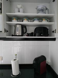 a kitchen with white cabinets and a shelf with dishes at Piso Pauser in Puentecesures