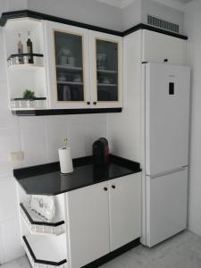 uma cozinha com armários brancos e um frigorífico branco em Piso Pauser em Puentecesures